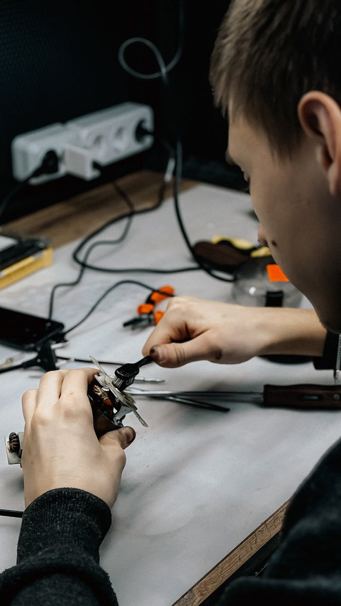A young technician working meticulously on electronic repairs at a workstation.